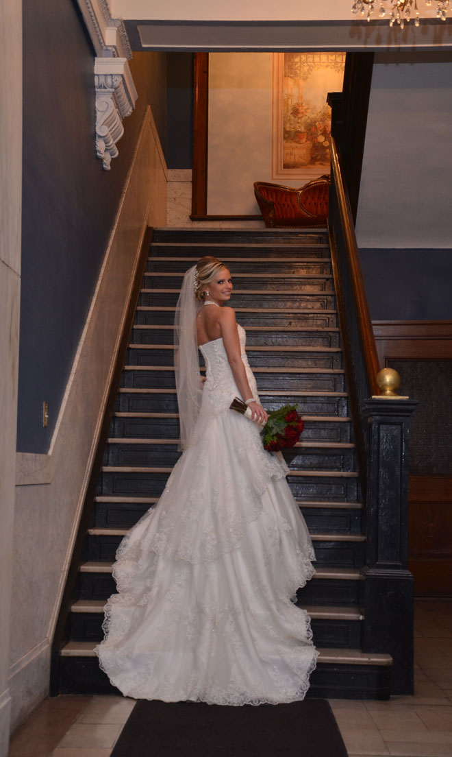 Bride models wedding dress on stairs of marble entrance at The Corinthian Event Center.
