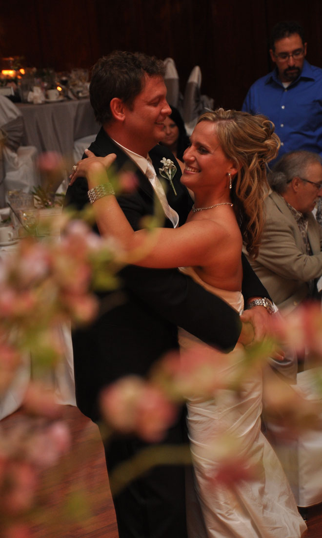Bride and Groom dance behind flowers in Grand Ballroom at The Corinthian Event Center.