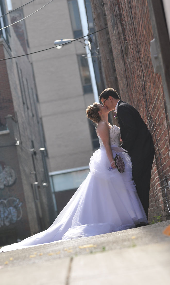 Bride and Groom kiss in alley at The Corinthian Event Center.