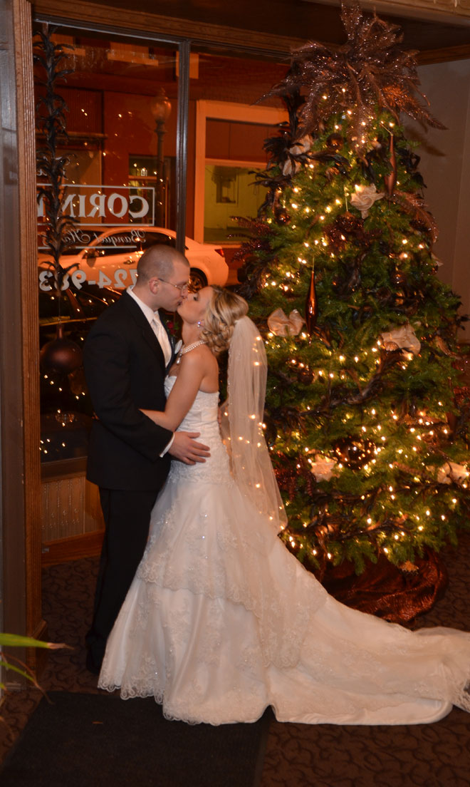 Bride and Groom kiss in lobby near a Christmass tree at The Corinthian Event Center.