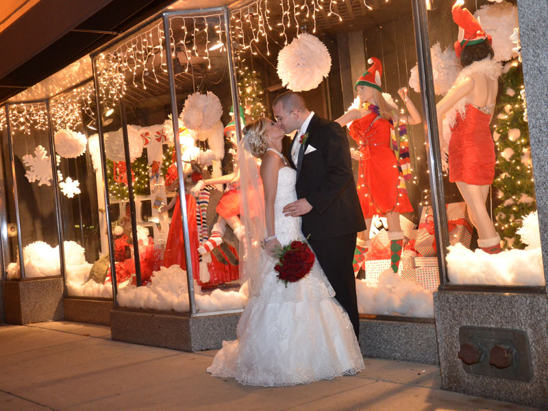 Bride and Groom kiss near Christmass display window at night near The Corinthian Event Center.