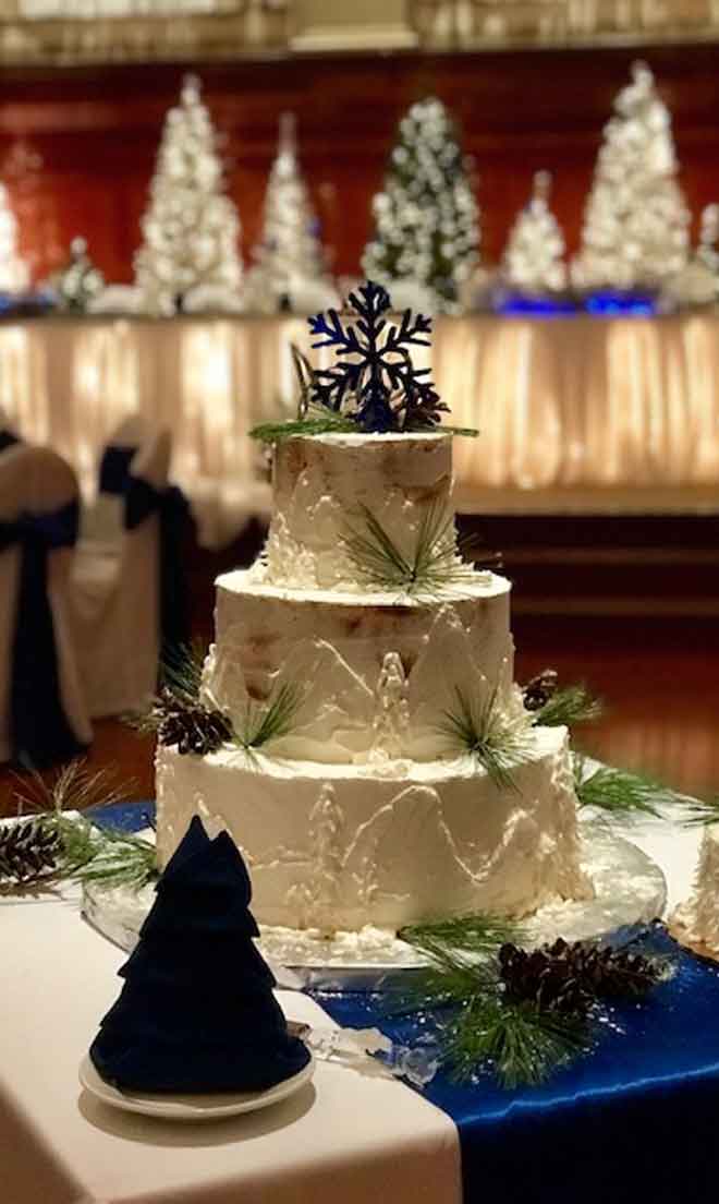 Cake table place setting with blue and white Christmass decor at The Corinthian Event Center.