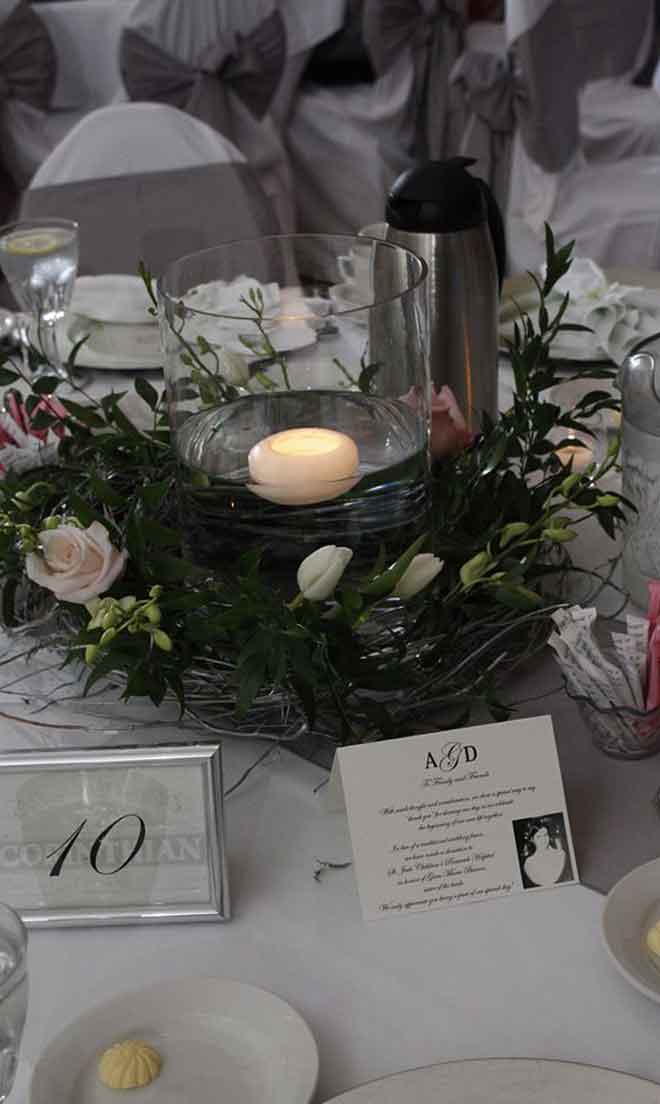 White theme lighted candle holder table centerpiece and place settings at The Corinthian Event Center.